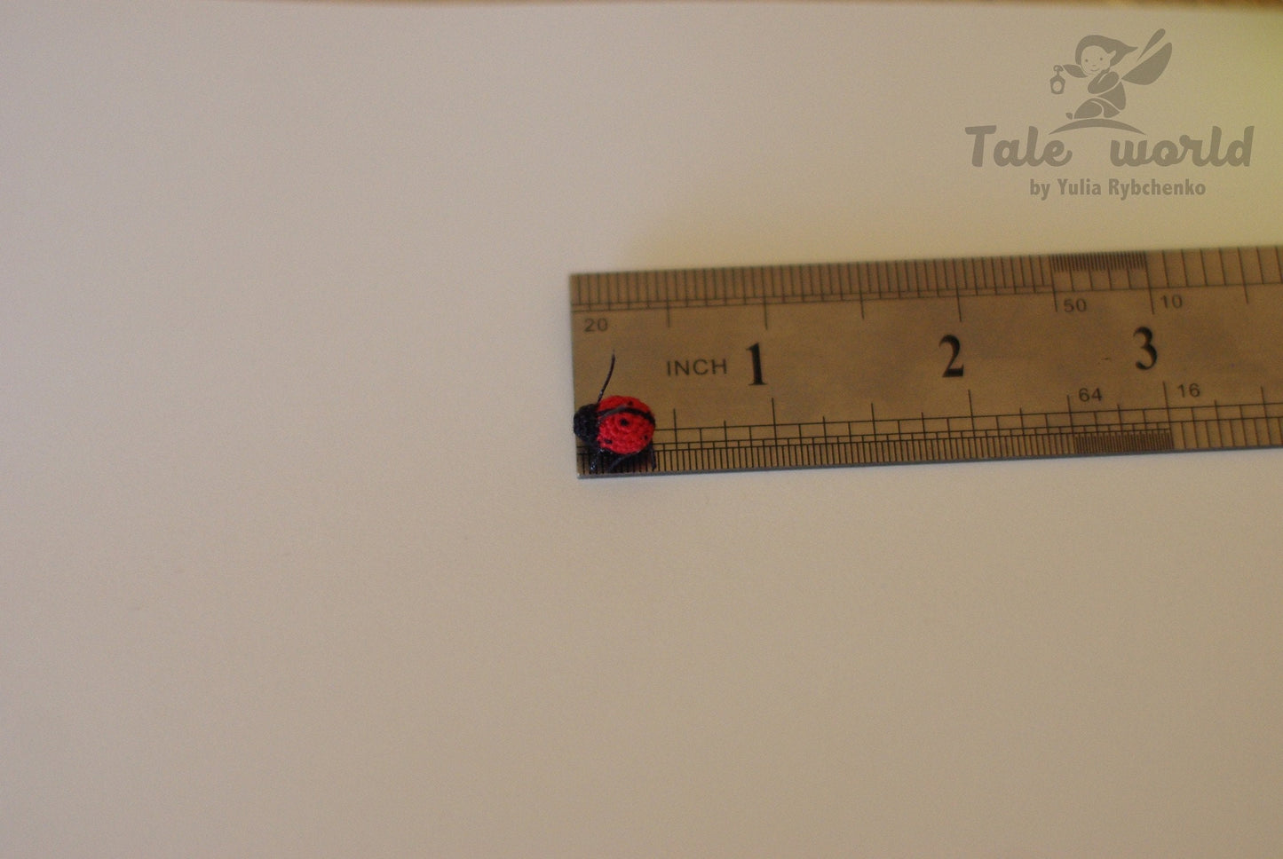 Small red and black object next to a ruler on a white background with 'Tale world' branding.