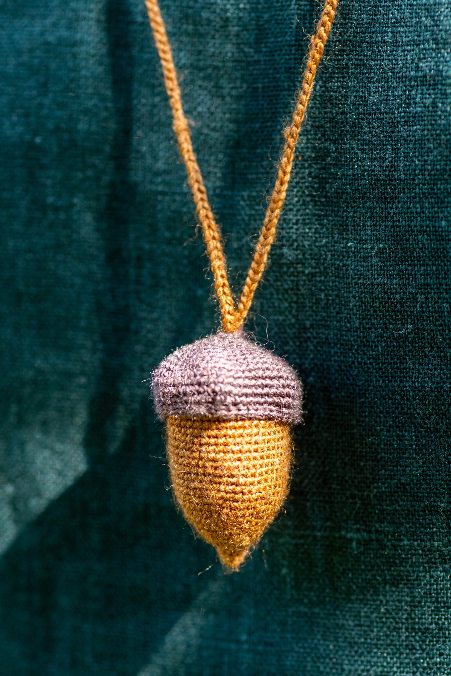 Knitted acorn pendant on a green textured background