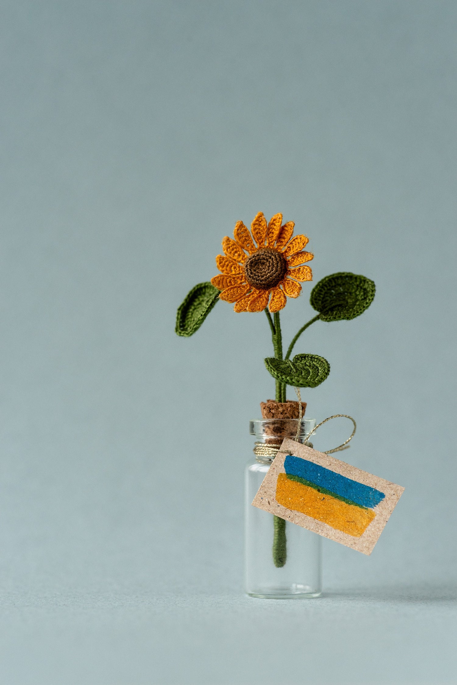 Miniature sunflower in glass bottle with Ukrainian flag tag
