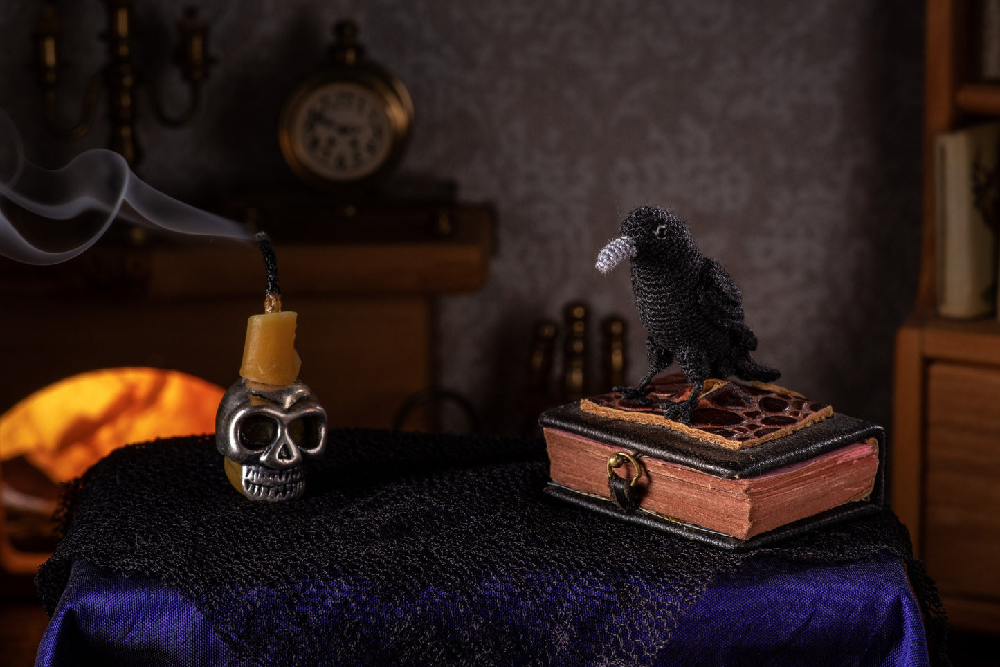 Miniature crochet raven on vintage book with candle skull, moody gothic setting
