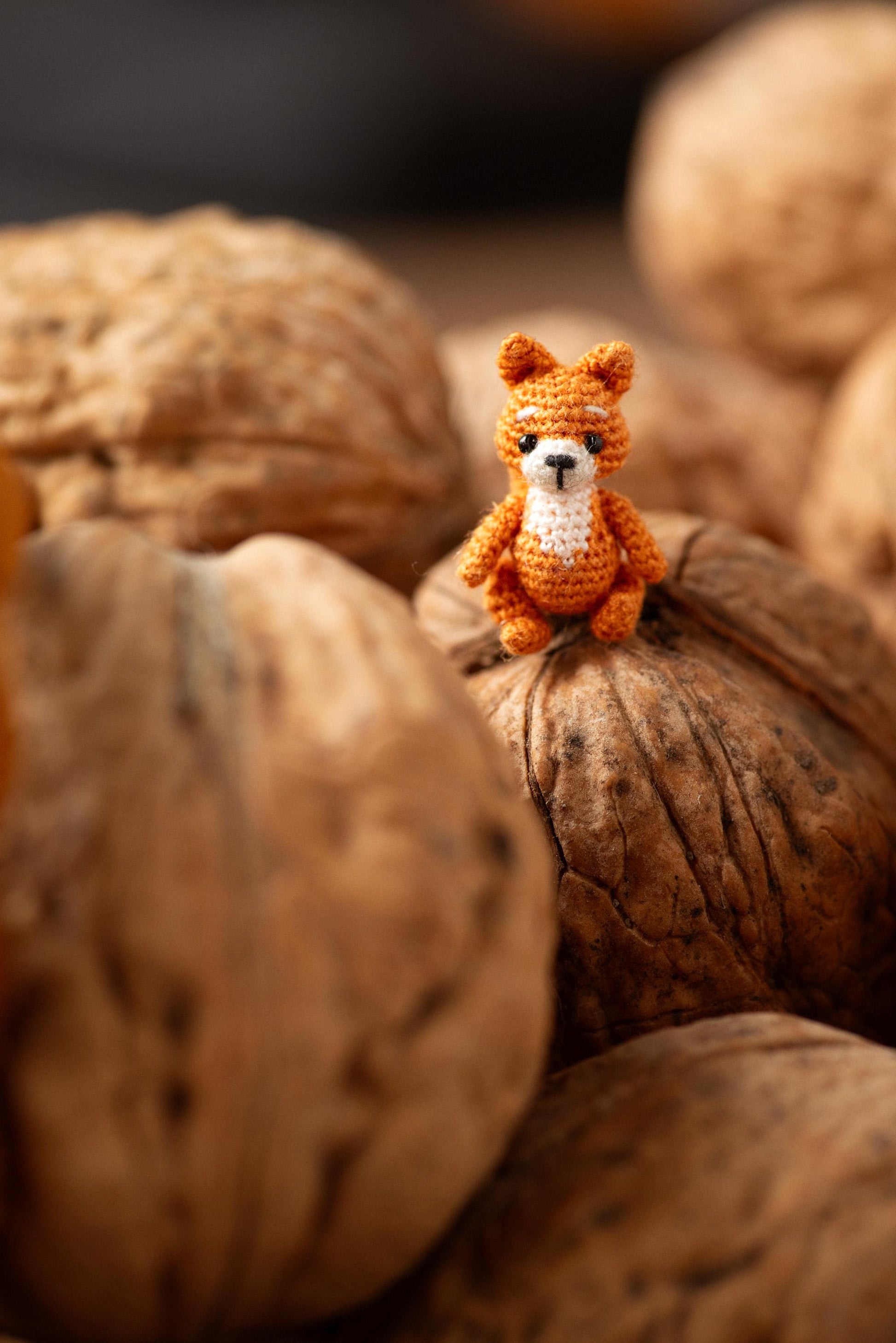 Small orange squirrel toy sitting on a pile of walnuts