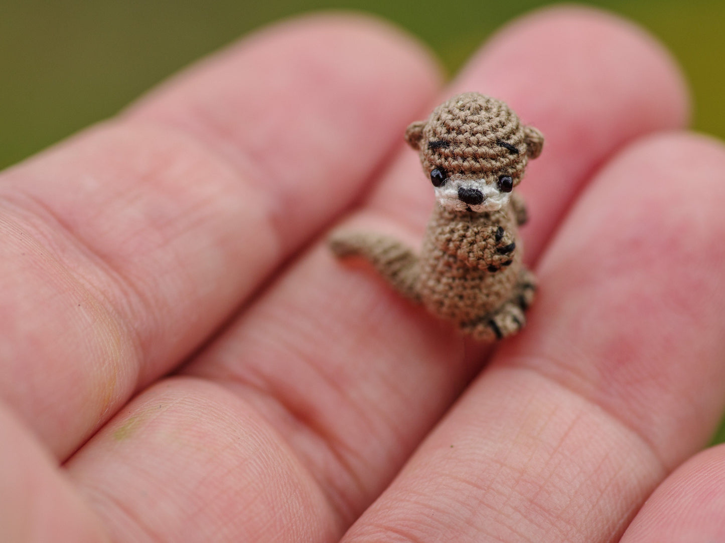 Tiny amigurumi otter with poseable tail in dreamy river-themed setting