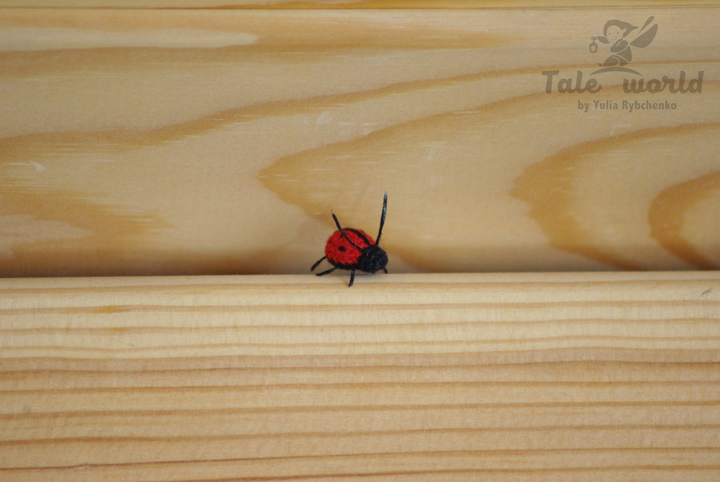 Red and black ladybug on a wooden surface with 'Tale world' branding.
