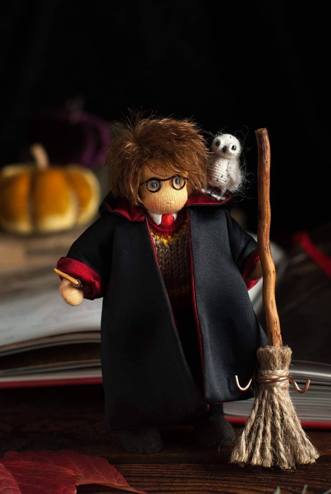 Toy figure of a character in a black robe with a broom and owl, set against a dark background.