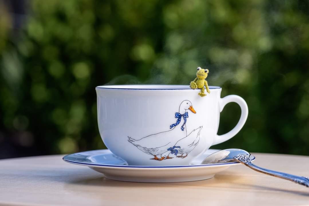 Tiny crochet frog sitting on a teacup