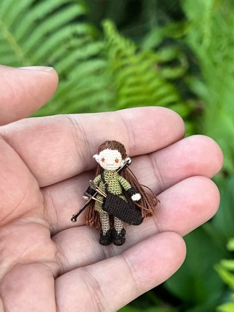 Tiny crocheted elf with bow and arrows in hand
