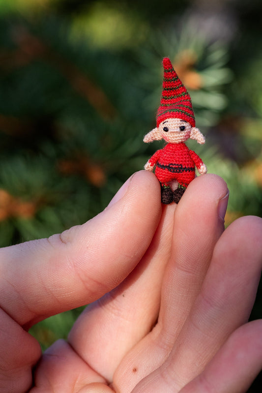Tiny crochet elf in red suit held in hand