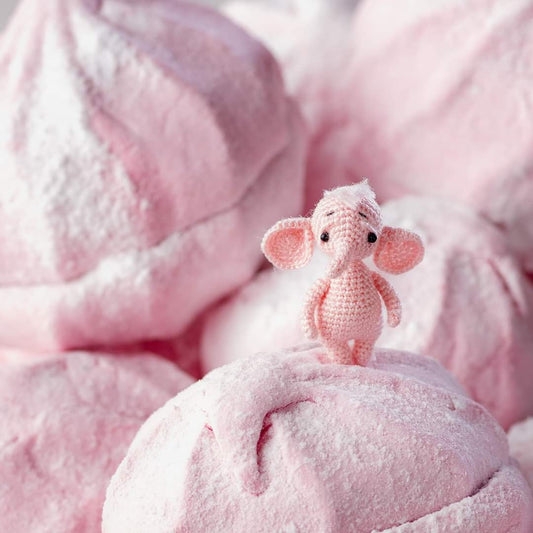 Tiny pink crochet elephant standing on pink marshmallows
