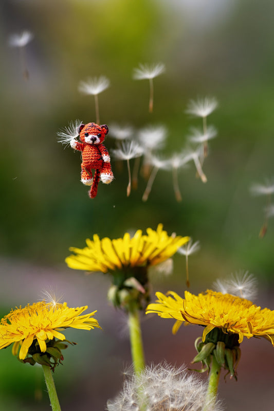 Tiny handmade crochet tiger with orange yarn and black stripes in outdoor setting
