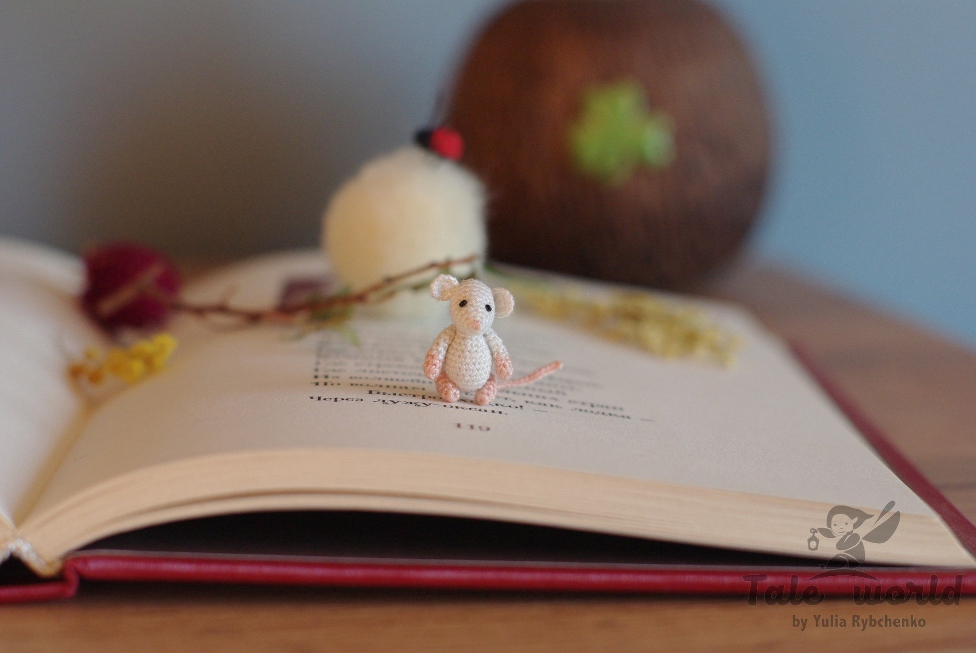 Tiny crochet rat sitting on an open book