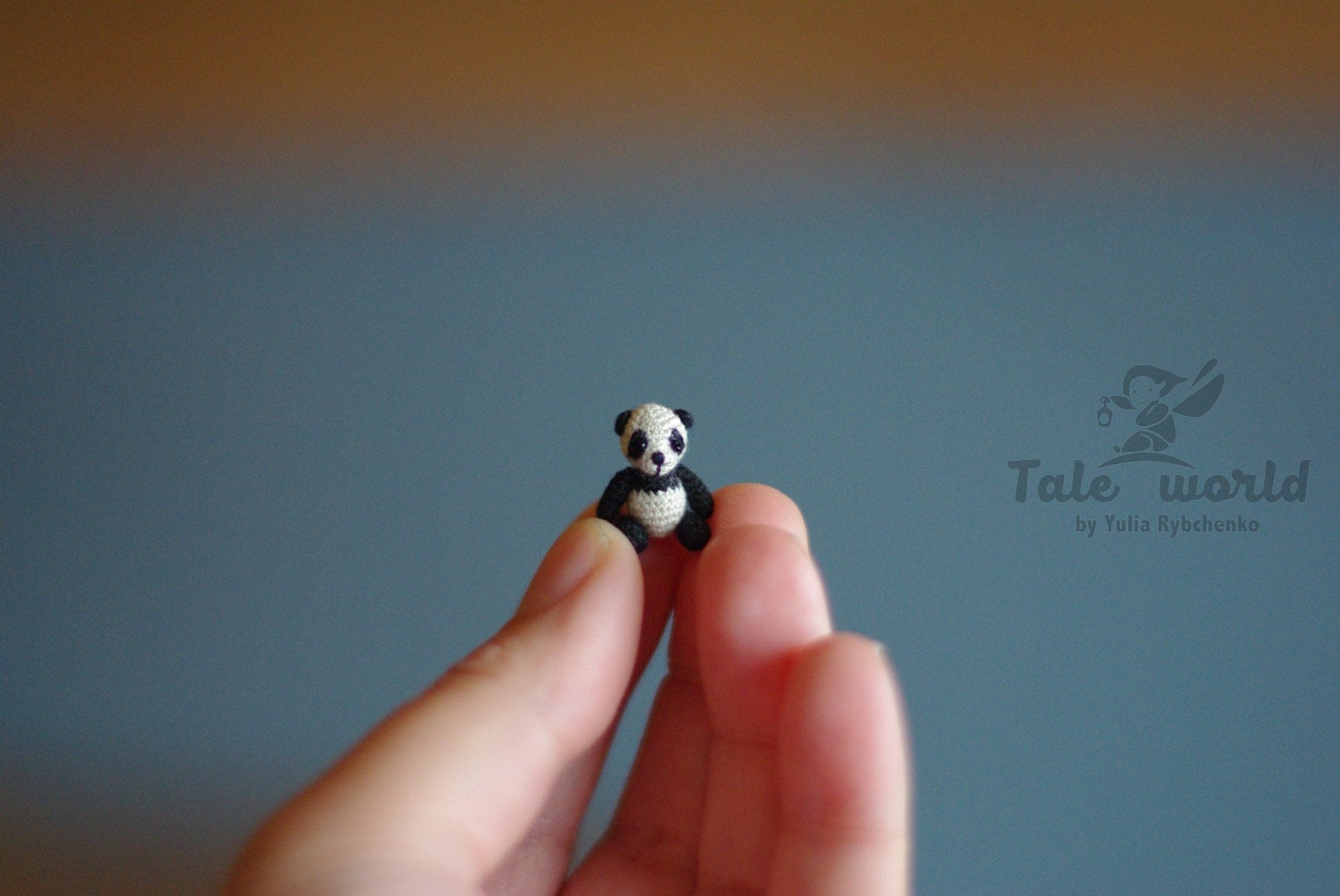 Tiny handmade panda bear resting in a human hand