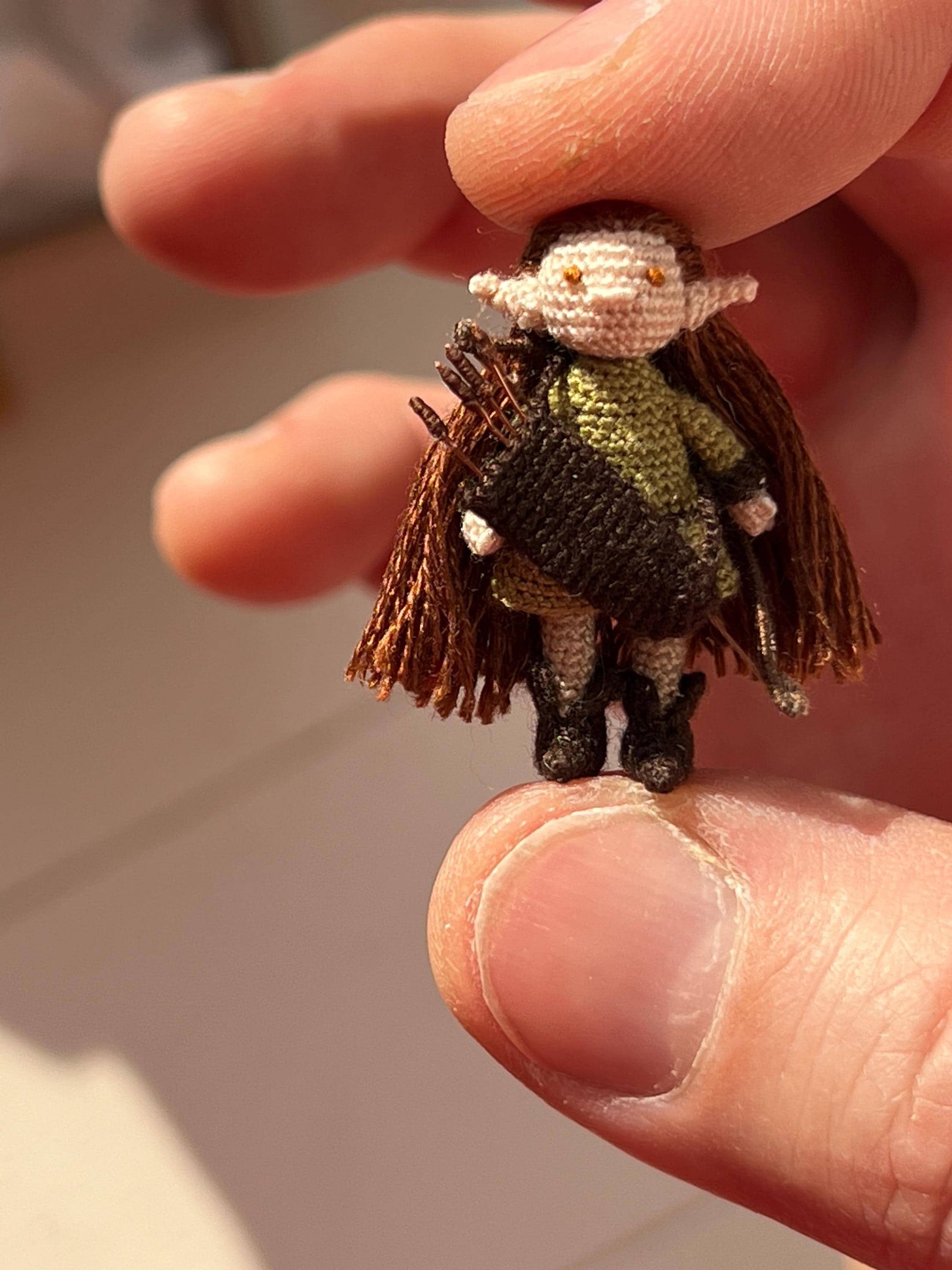 Forest elf doll in green outfit holding black bow