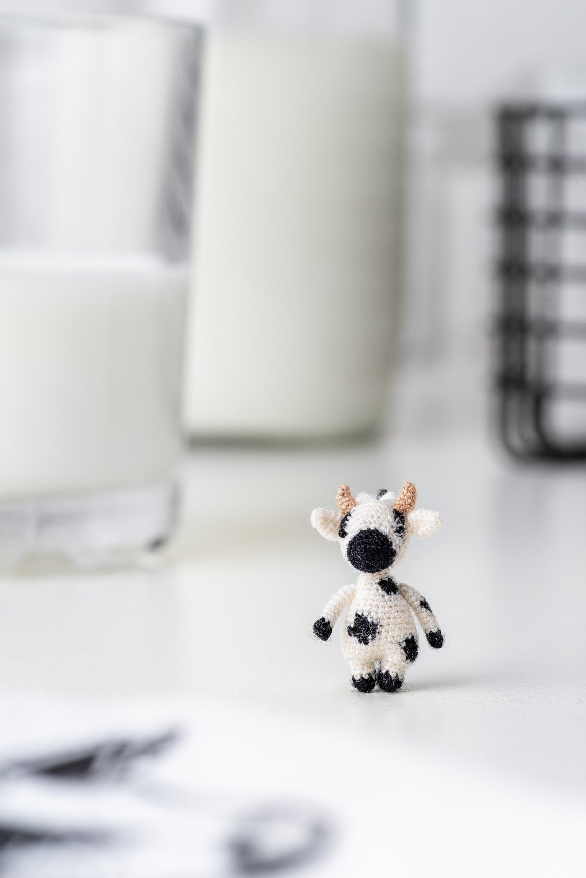 Tiny black and white crochet cow on white background