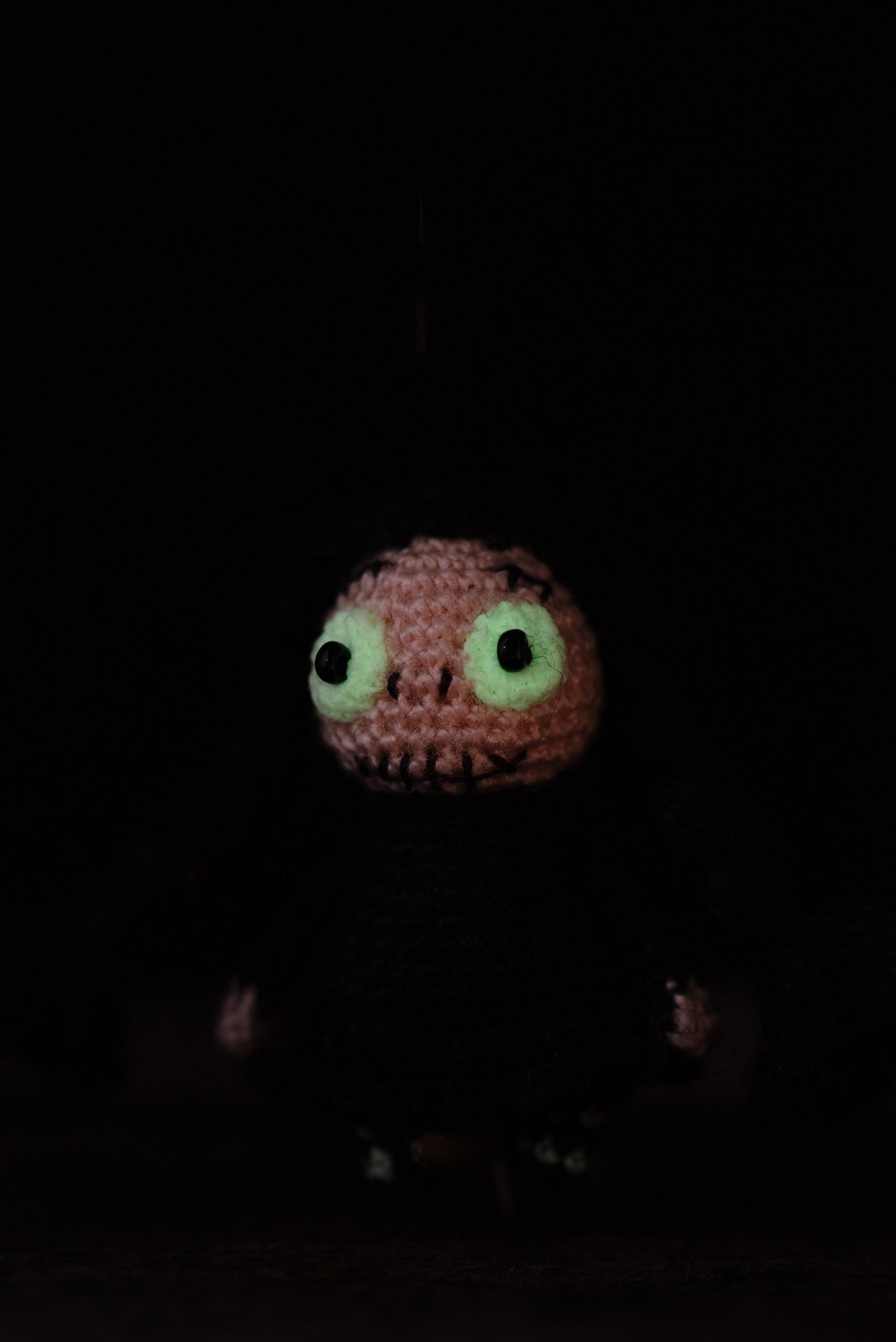 Miniature crochet gothic doll with black braids and luminous glow-in-the-dark eyes