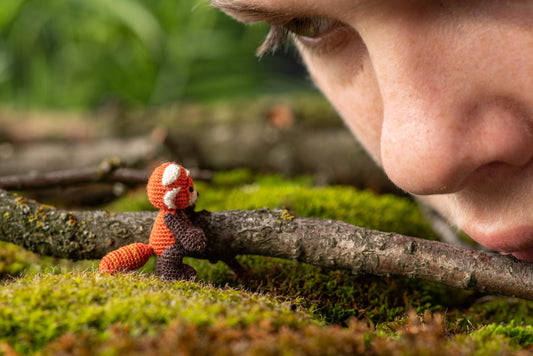 Miniature amigurumi red panda with black body and orange head
