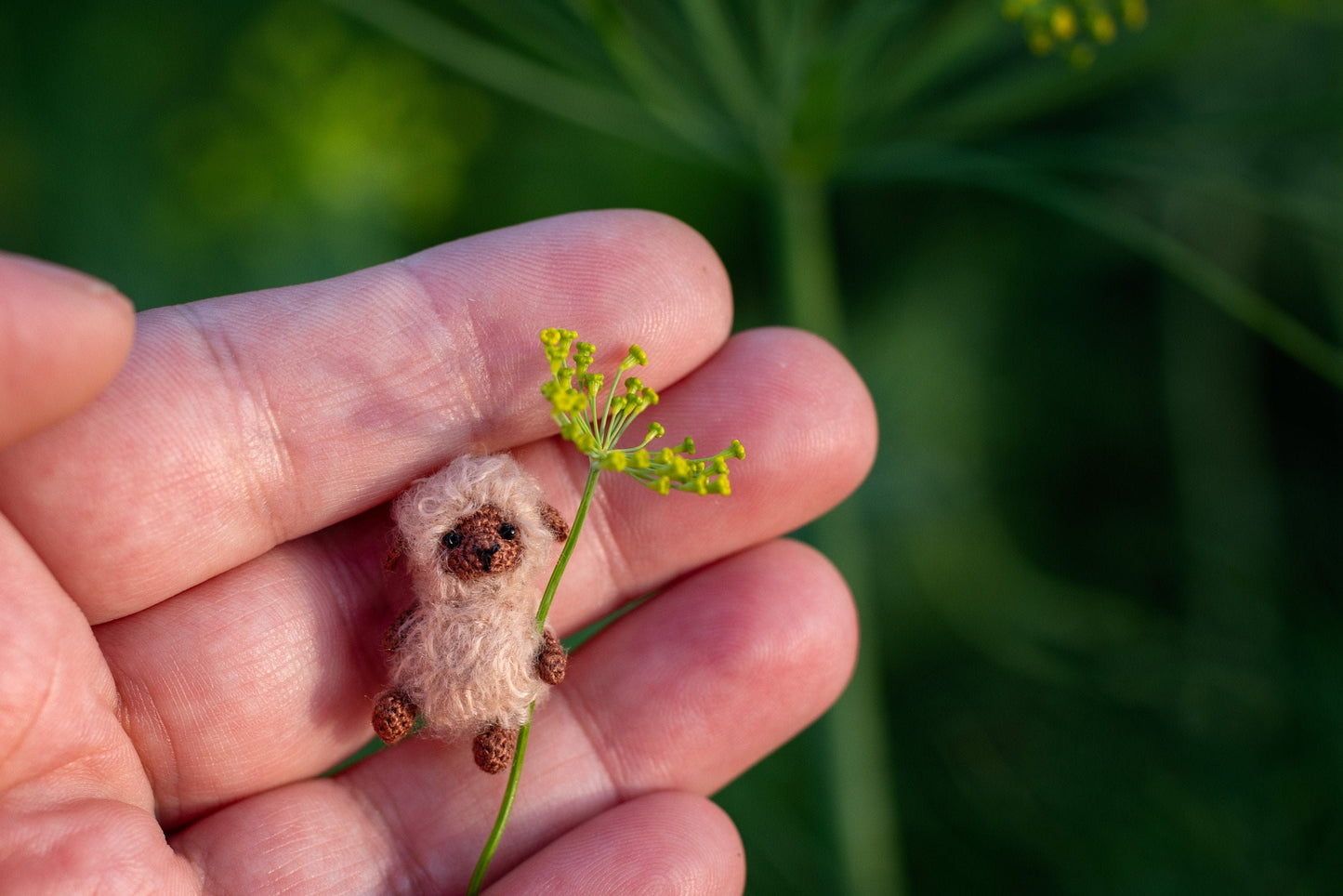 Tiny crochet sheep holding a handmade flower