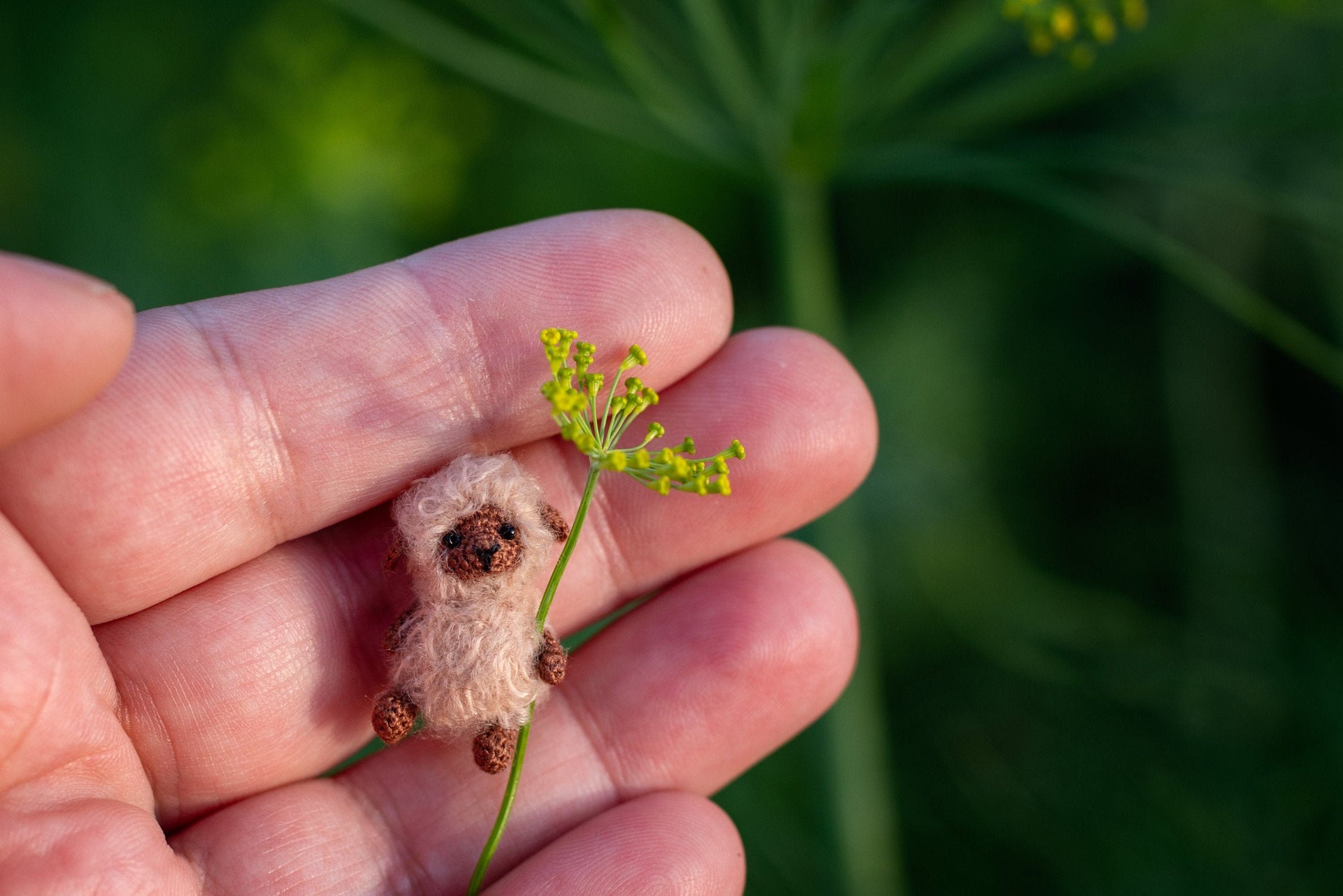 Tiny crochet sheep holding a handmade flower