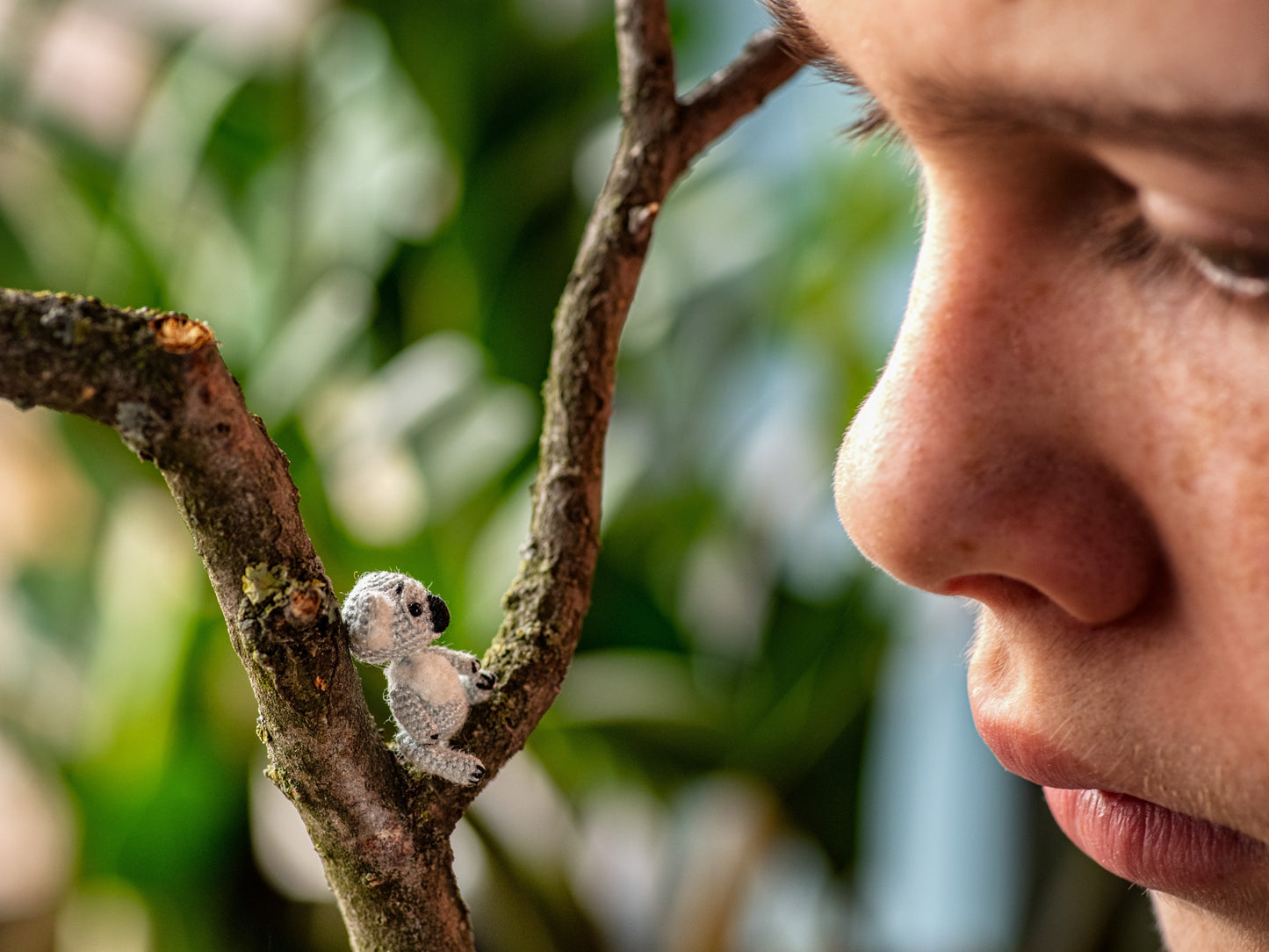 Tiny crochet koala looking up at a child
