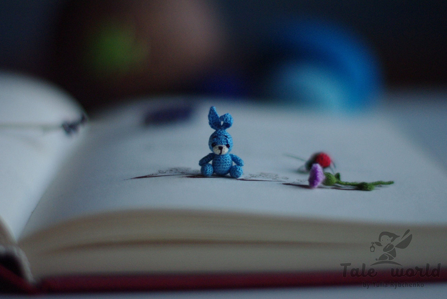 Sky blue amigurumi bunny surrounded by periwinkle blooms on white background