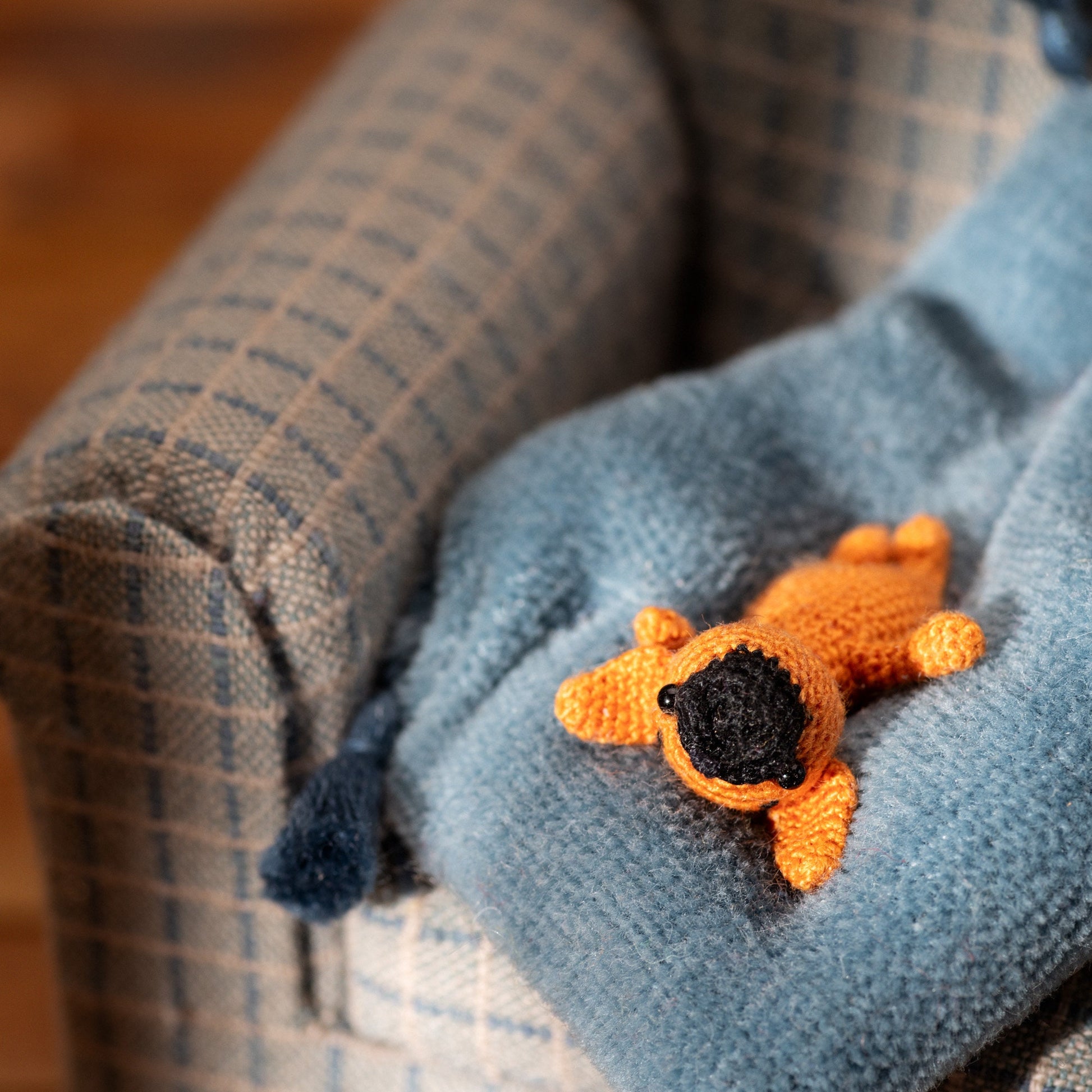 Tiny crochet French bulldog lying on a miniature blue blanket