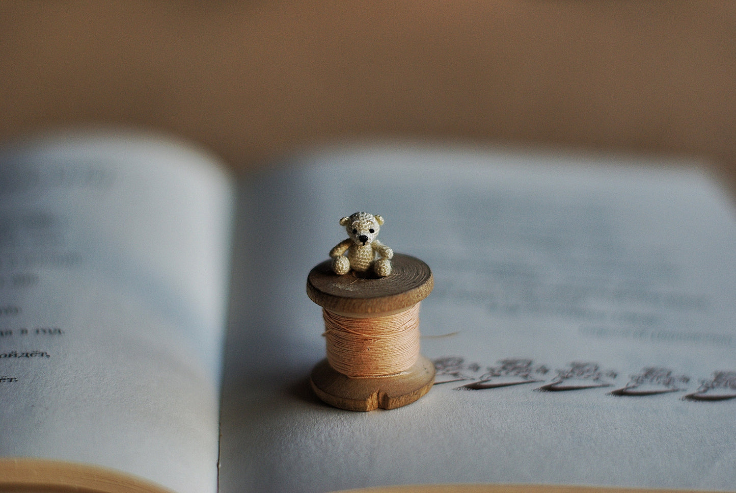Tiny beige teddy with stitched paws and black eyes on blue background