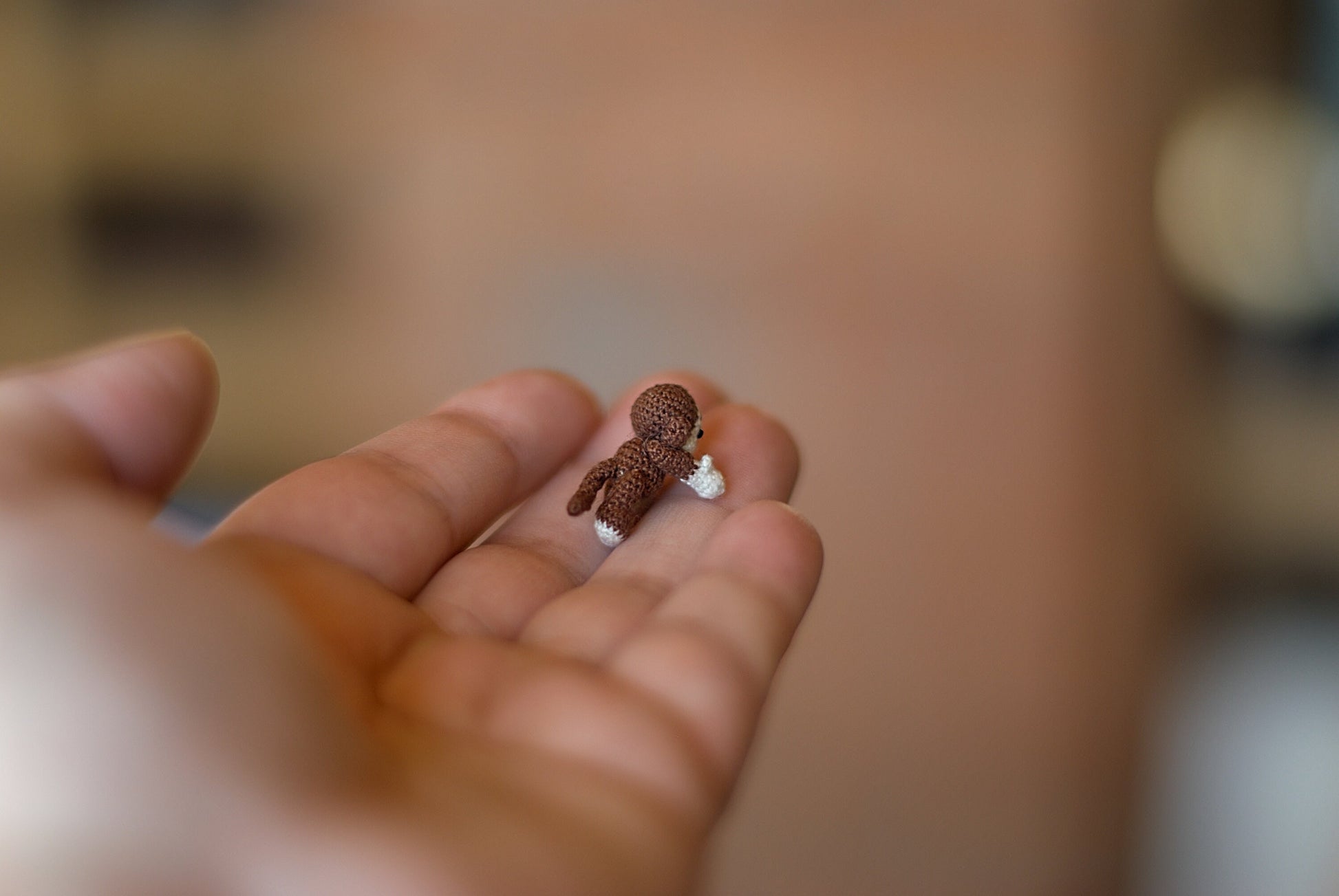 Miniature amigurumi monkey sitting playfully on a human hand