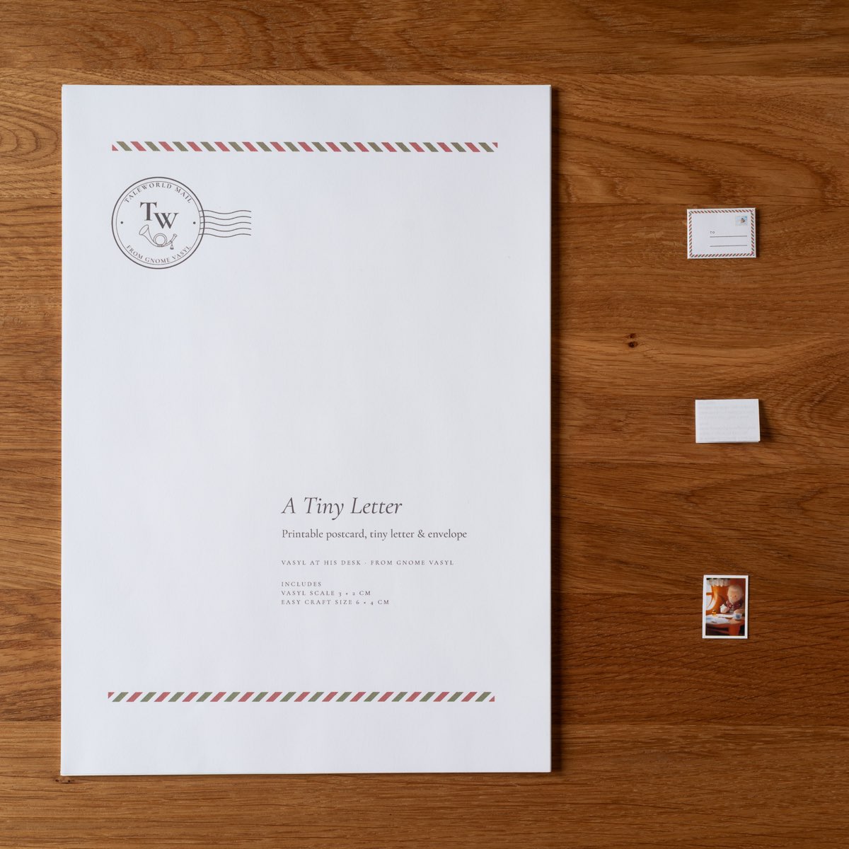 The title page of the set on a wooden table, airmail stripes across its head and foot, with the three miniature pieces lying beside it.